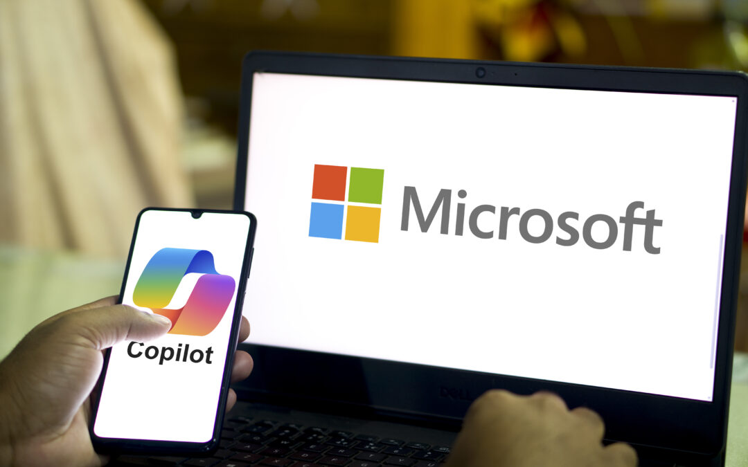 Microsoft Copilot on phone, Microsoft logo on laptop screen.